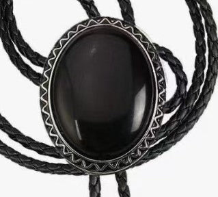 The Western Express Black Stone Bolo Tie features a large oval black centerpiece and braided leather cords with silver tips—a bold cowboy jewelry piece and classic western accessory.