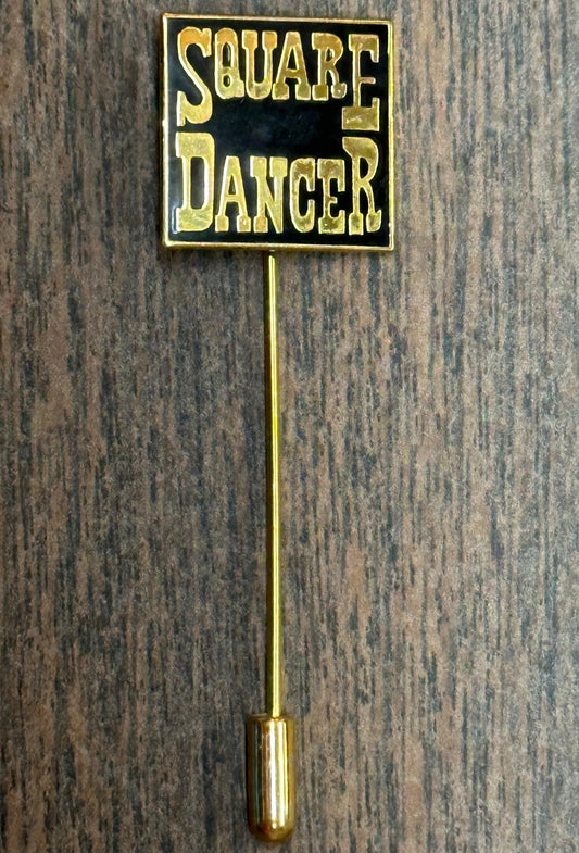 The Square Up Fashions Square Dancer Stick Pin features a black and gold rectangular "Square Dancer" plaque on a long gold stick with cap, perfect as jewelry for dancers, shown on a wooden surface.