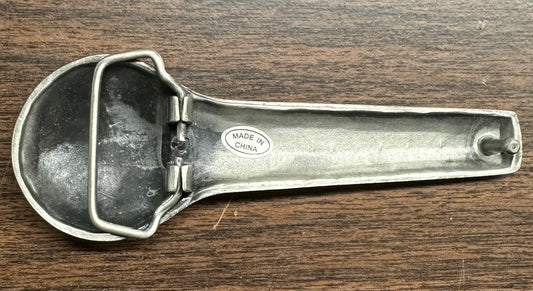 The SD Callers’ Belt Buckle by Square Up Fashions has a sturdy design that is reminiscent of a metal ice cream scoop with a hinged lever, complete with a “Made in China” label.
