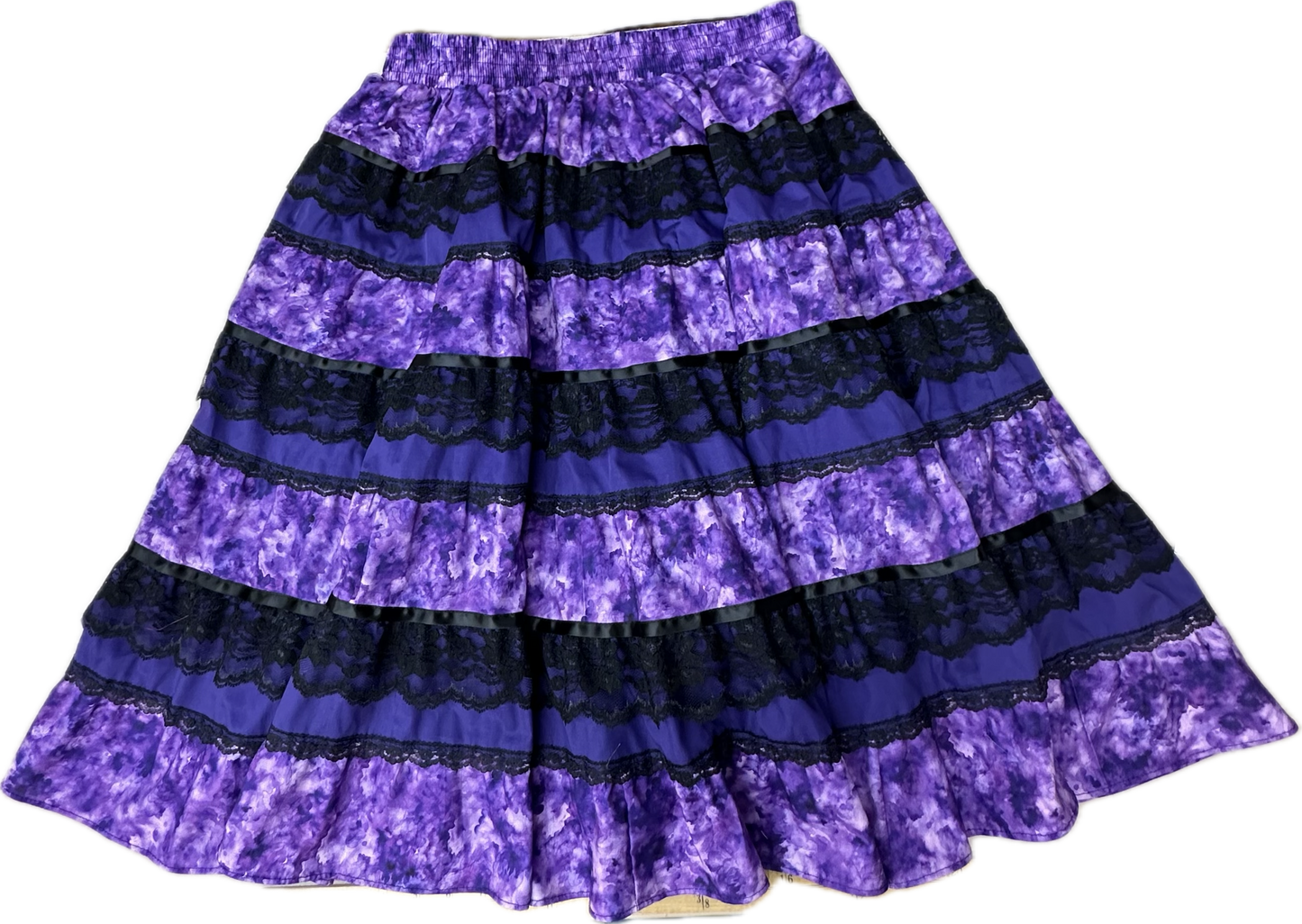 The Tone on Tone Prairie Skirt by Square Up Fashions features alternating bands of purple tie-dye and black lace, making this standout black lace skirt a stylish addition to any women's wardrobe.