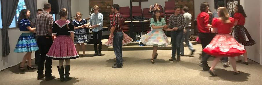 Square dancers in colorful petticoats dancing in a hall