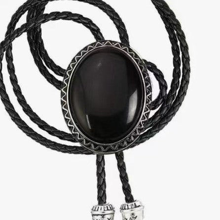 The Western Express Black Stone Bolo Tie features a large oval black centerpiece and braided leather cords with silver tips—a bold cowboy jewelry piece and classic western accessory.