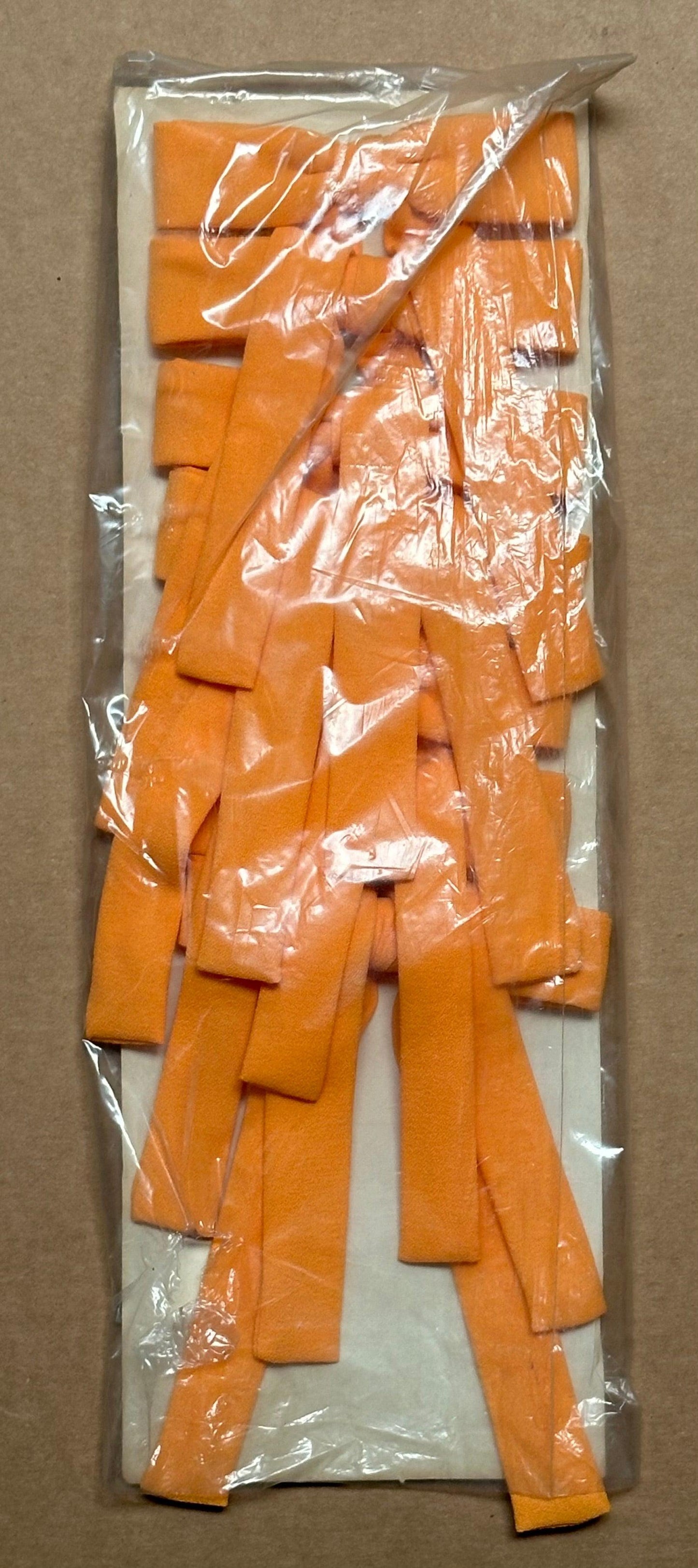 A sealed plastic bag from Square Up Fashions contains several bright orange foam accessories named Colonel Ties, designed to resemble a bold southern bow tie when laid on a flat surface.