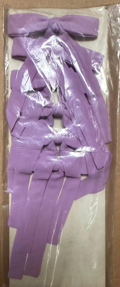 A collection of Colonel Ties ribbons by Square Up Fashions, featuring a western-inspired design in purple, is neatly organized in a pattern and showcased in a plastic package.