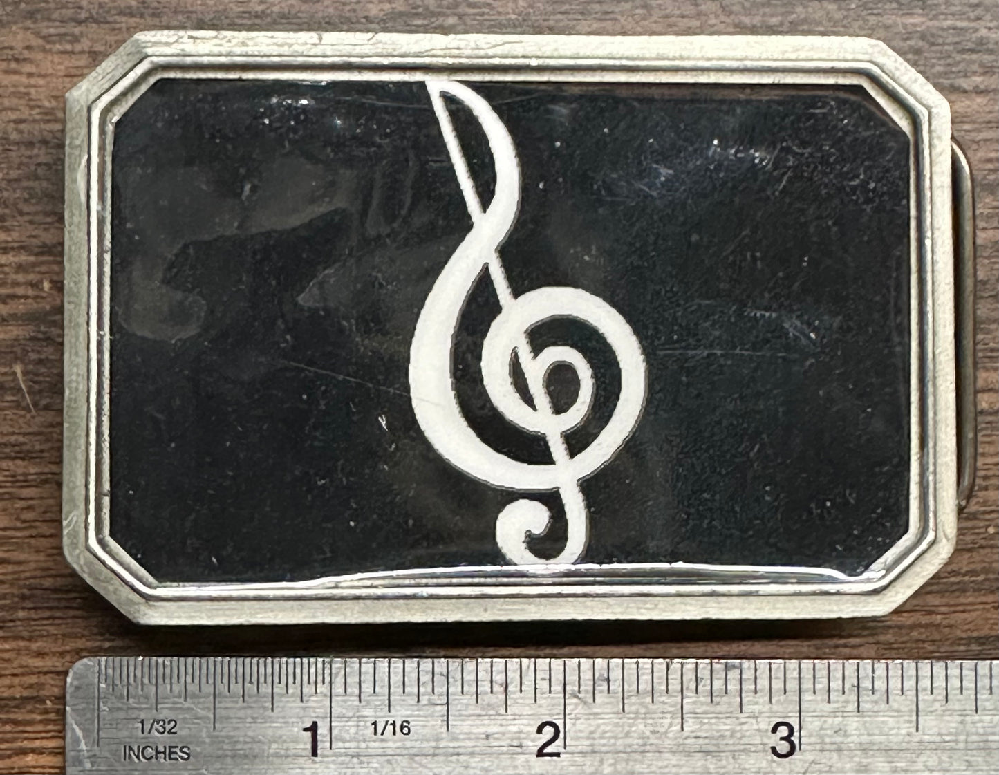 The Square Up Fashions Music Note Belt Buckle is a rectangular metal accessory featuring a white treble clef on a black background, measuring about 3 inches wide.