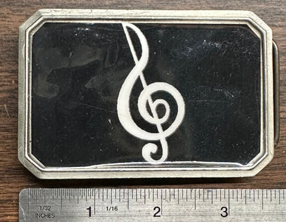The Square Up Fashions Music Note Belt Buckle is a rectangular metal accessory featuring a white treble clef on a black background, measuring about 3 inches wide.