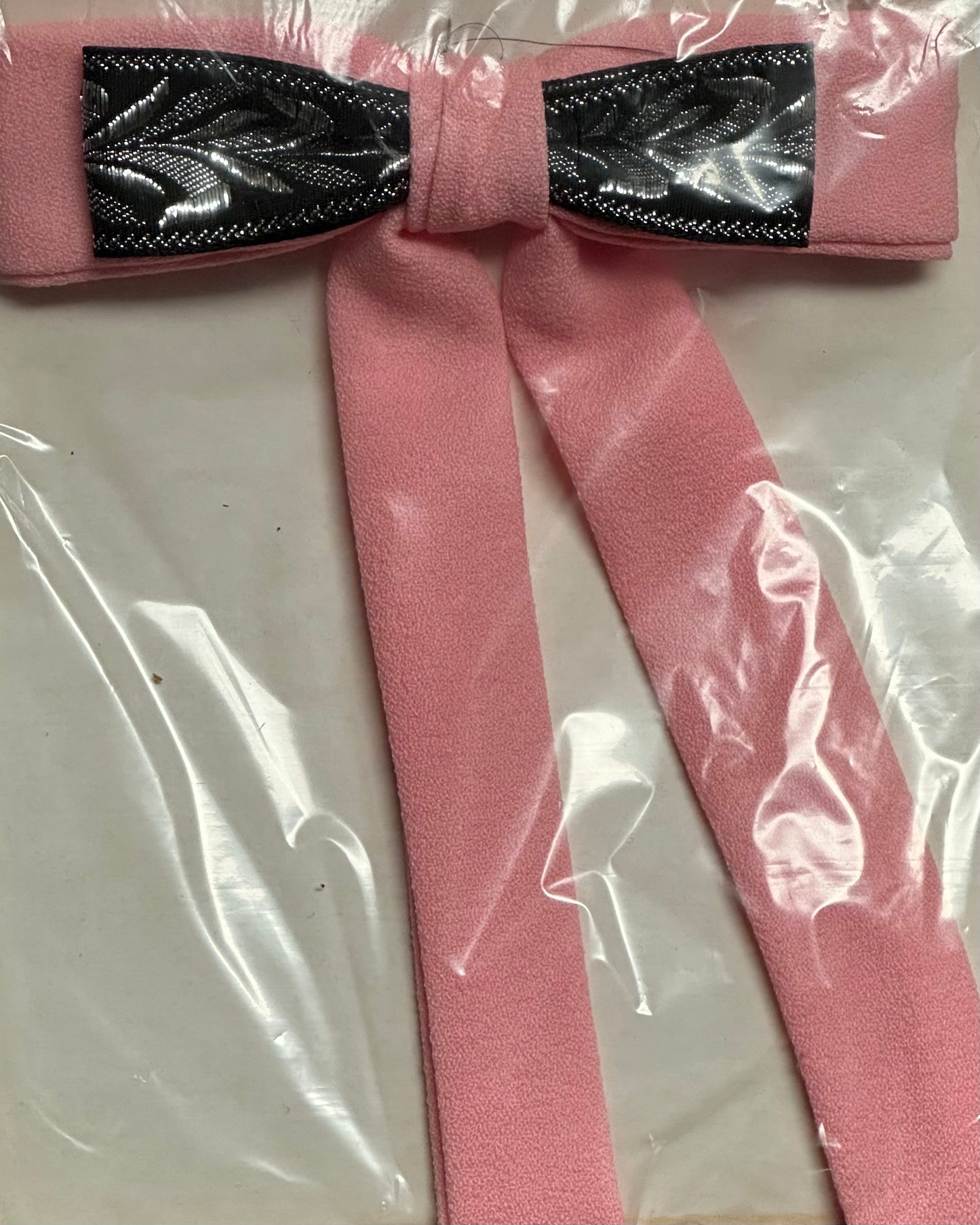 A pink Colonel Tie, featuring long tails and a striking black and silver center design, inspired by traditional southern bow ties, elegantly displayed on a white background, from Square Up Fashions.