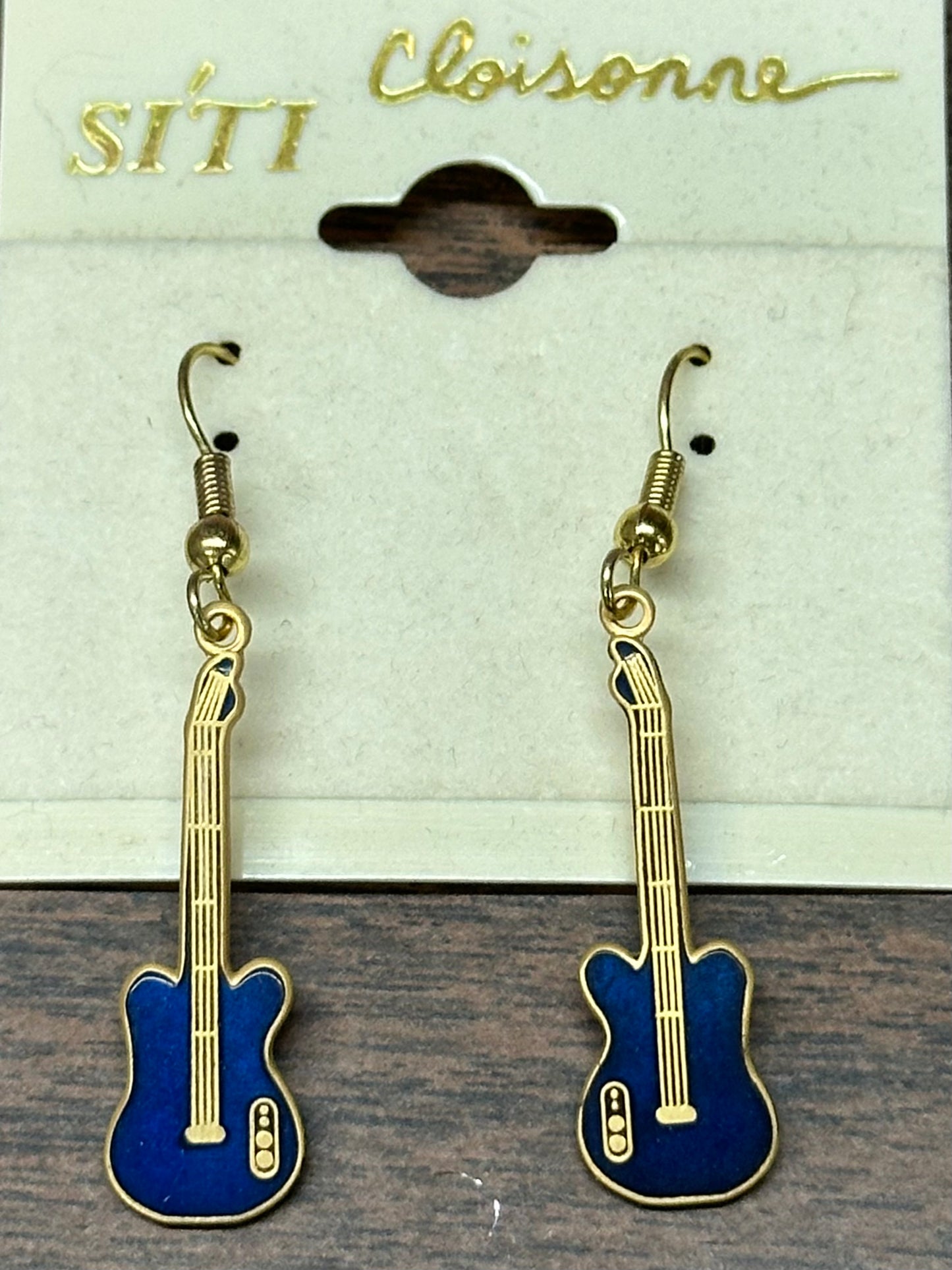 A pair of blue and gold, music-themed Guitar Dangle Earrings graces a card labeled "Square Up Fashions," capturing the essence of Western jewelry with their intricate design.