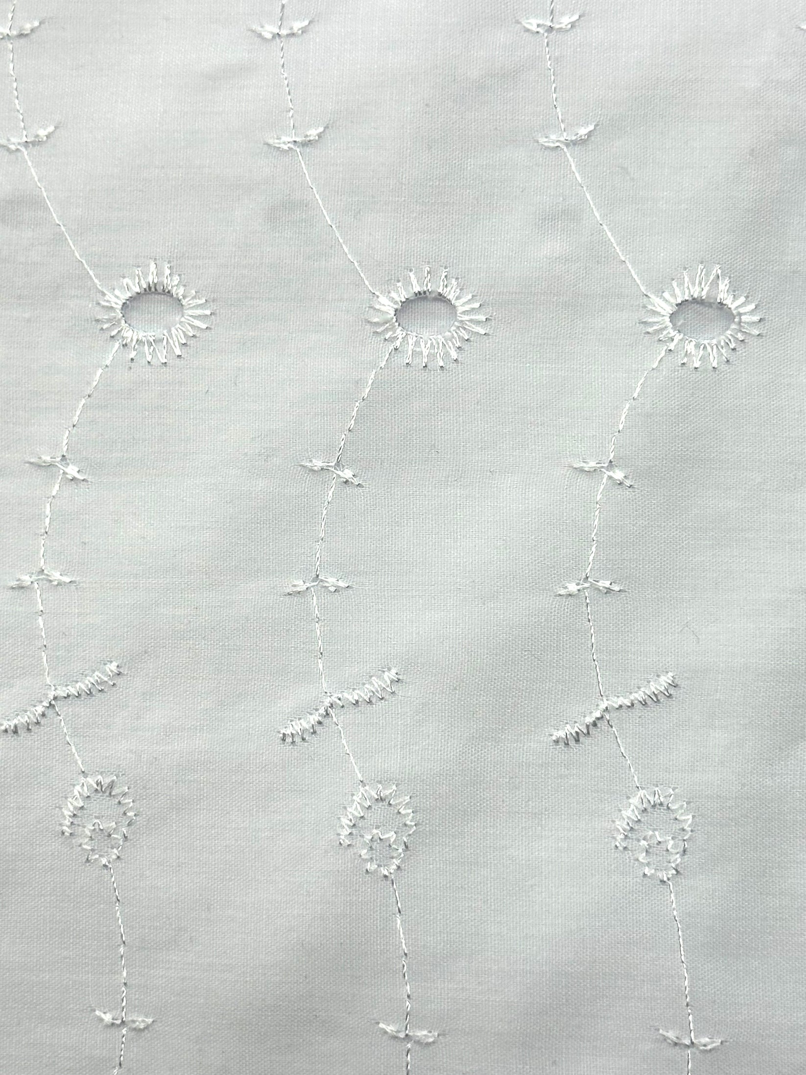 The Eyelet Patchwork Square Dance Skirt by Square Up Fashions features white fabric embroidered with circular floral patterns and wavy lines—ideal for tiered or eyelet lace skirts.