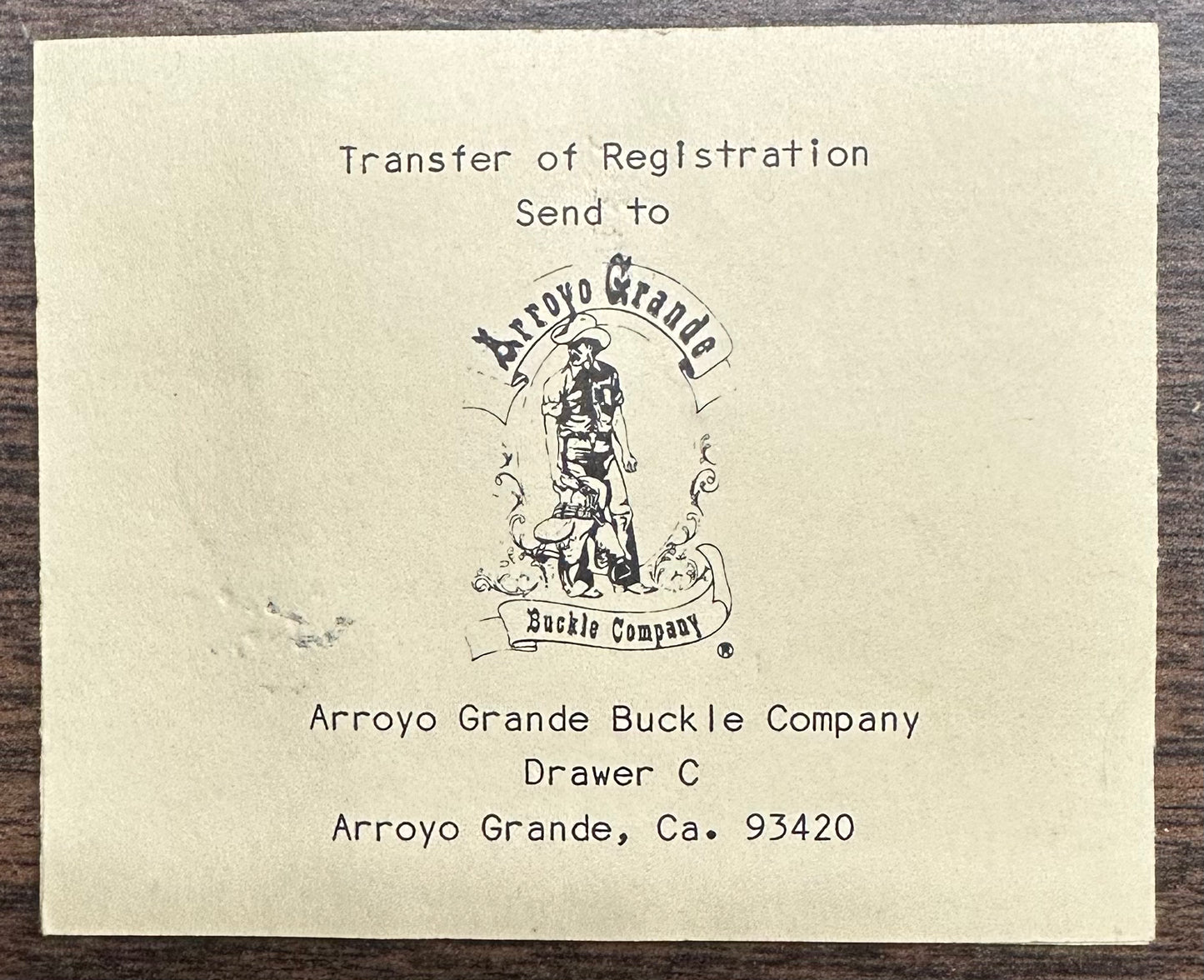 A printed card for the Square Dance Buckle w/caller by Square Up Fashions instructs to send transfer of registration to Arroyo Grande Buckle Company, Drawer C, Arroyo Grande, CA 93420. Features company logo. Made in USA.