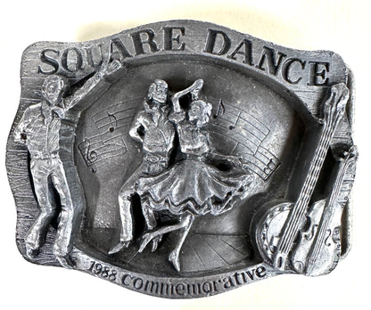 Square Up Fashions' "Square Dance Buckle w/ instruments"—a vintage metal plaque with dancers, musical notes, and double bass, commemorating the 1988 National Square Dance in Anaheim. Perfect for square dance collectors!.