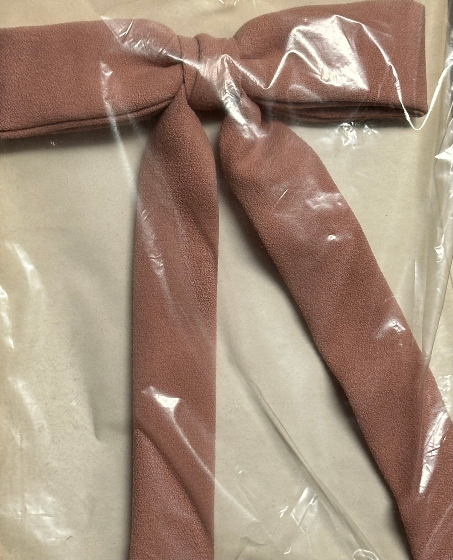 A large brown Colonel Tie by Square Up Fashions, echoing the style of a classic southern bow tie, wrapped in protective plastic.