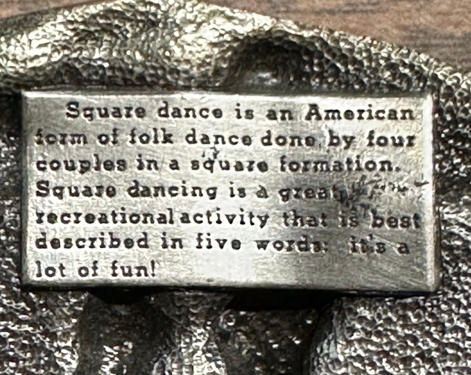 A metal plaque explains that square dance, an American folk dance of four couples in a square, is a lively, recreational activity—just as the Square Up Fashions Square Dance Buckle w/ instruments celebrates this tradition.