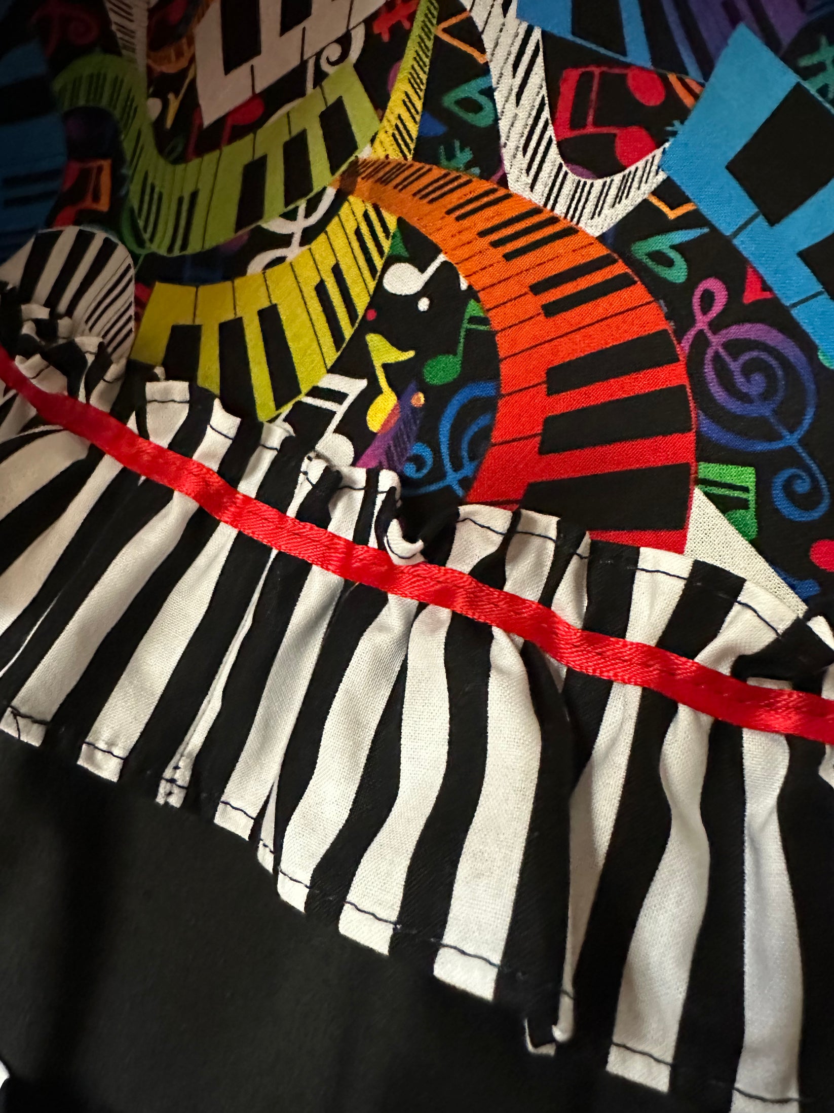 Close-up of the Musical Square Dance Outfit by Square Up Fashions, featuring exclusive colorful swirling piano key stripes, ruffled piano key trim, and a red ribbon—perfect for standing out. Only a few left!.