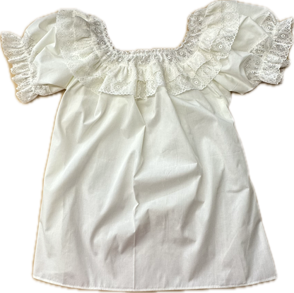 The Fiesta Laced Round Neck Blouse by Square Up Fashions features white cotton, short ruffled fiesta lace sleeves, and a delicate lace ruffle at the neckline, shown laid flat on a plain background.