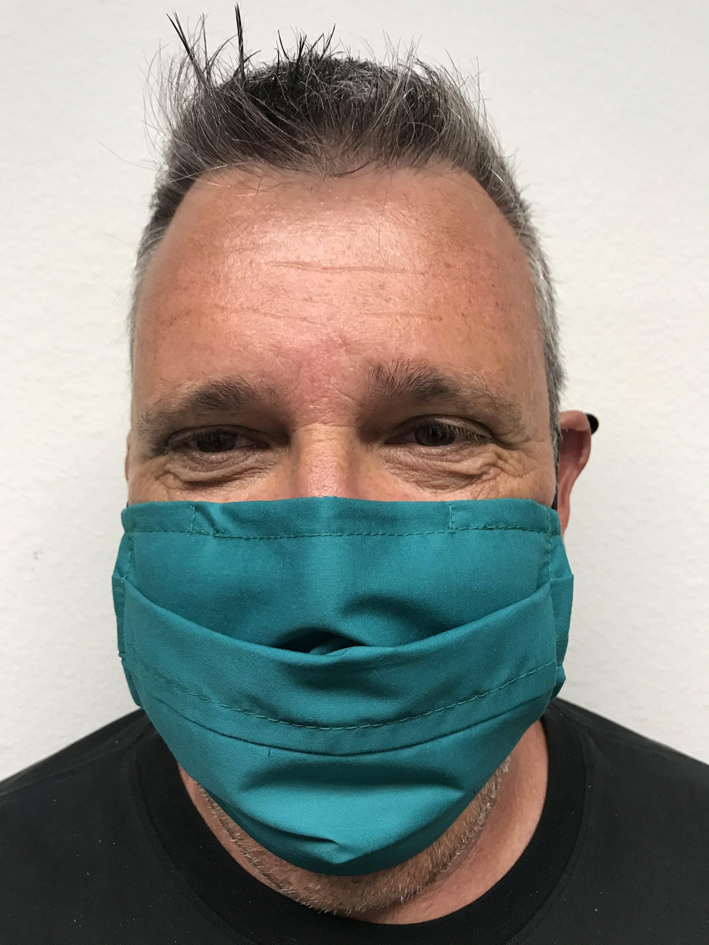 A man wearing a Square Up Fashions green face mask with adjustable nose wire, providing 2 layers of protection. The mask is washable & reusable.